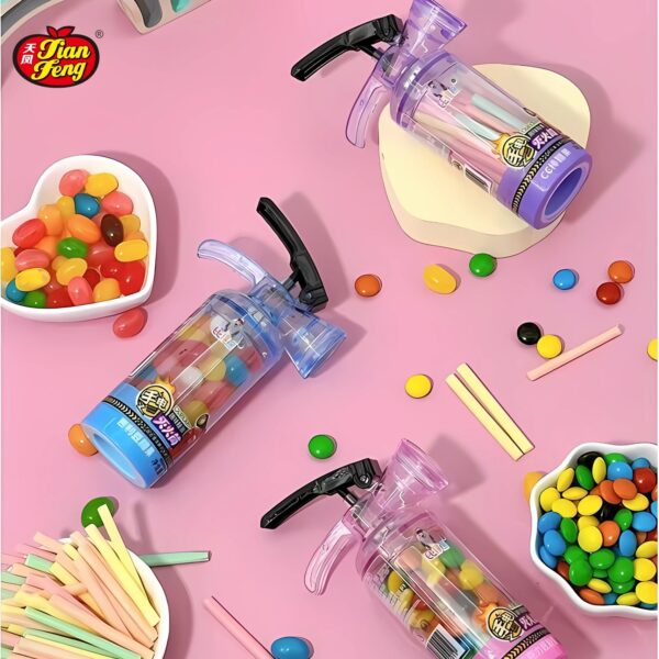 Three colorful Fire extinguisher bottles with candy inside are displayed on a pink surface. Surrounding them are various candies, including jellybeans milk chocolate beans and candy cc sticks.